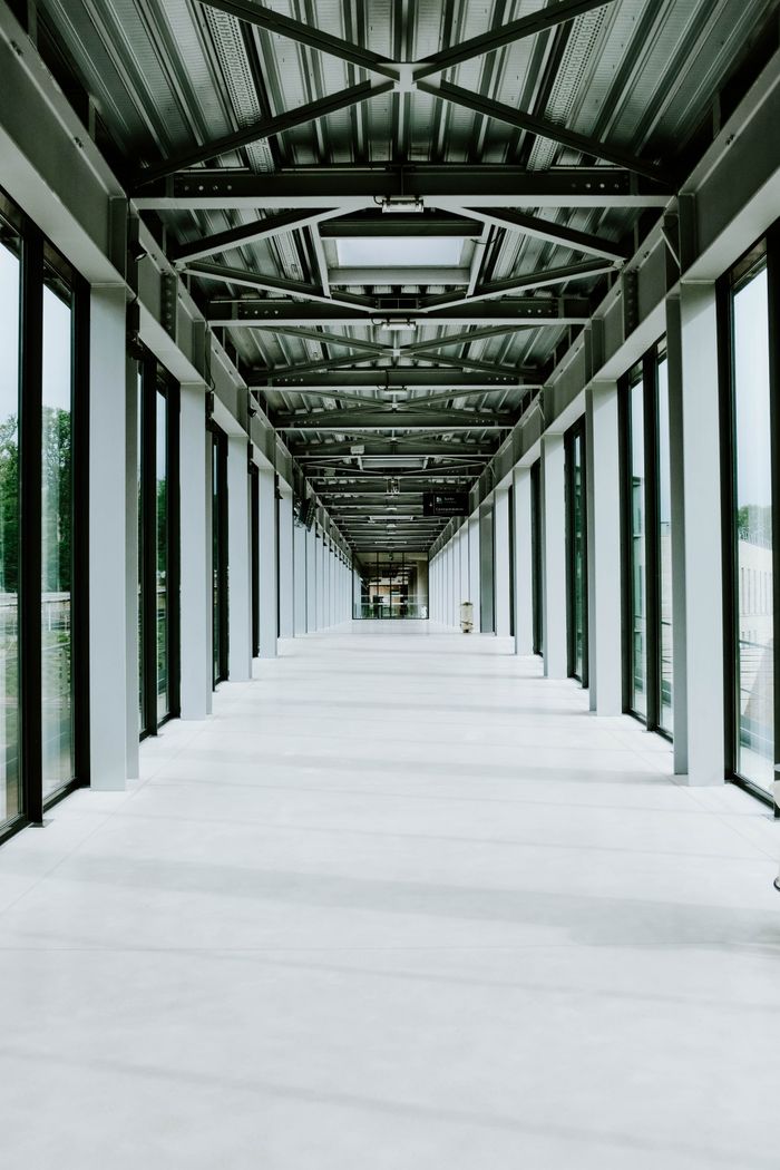 Expansive modern corridor with glass walls and exposed steel beams, creating a sleek architectural view.