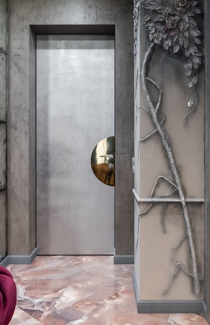 Entrance of modern corridor with tiled floor and gray door with column with ornamental decorative floral elements in contemporary apartment