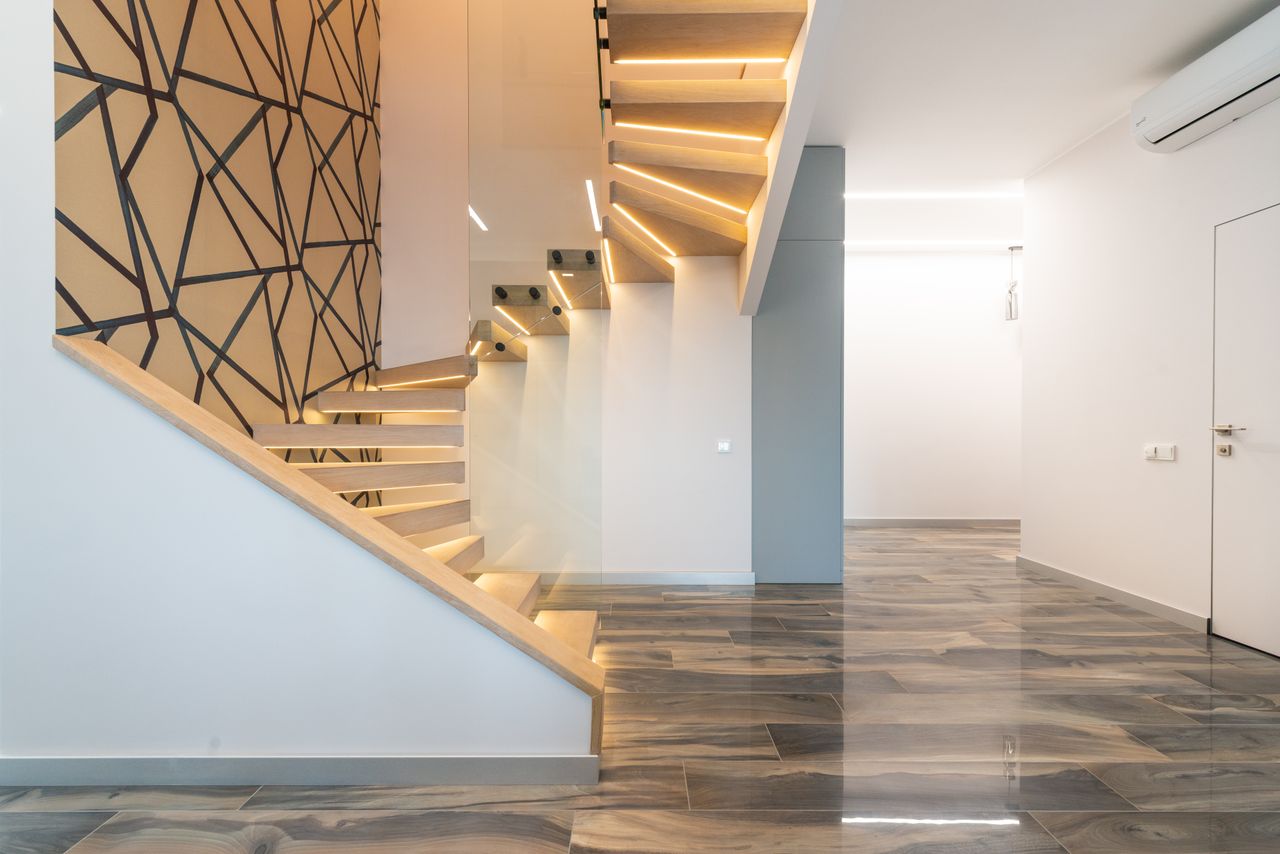 services-02 Contemporary hall interior with door against curved staircase and wall with geometric ornament in light house